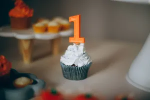 Blue cupcake with white frosting and orange number 1 candle, ideal for a first birthday celebration. jigsaw puzzle
