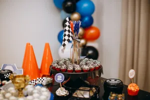 Racing themed party table with cupcakes, balloons, and checkered flags creating a festive atmosphere. jigsaw puzzle