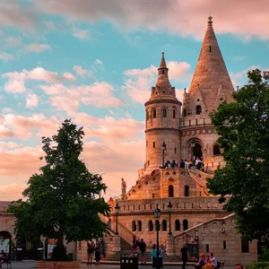 Stunning view of Fisherman's Bastion in Budapest with vibrant sunset sky and people exploring the landmark. jigsaw puzzle