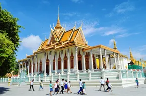 Ornate Asian palace exterior with people walking by on a sunny day, featuring intricate architecture. jigsaw puzzle