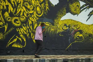 A senior man with a mask walks past a vivid mural, holding an umbrella in the rain. jigsaw puzzle