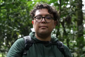 Portrait of a hiker surrounded by dense green jungle, wearing glasses and a green hoodie. jigsaw puzzle