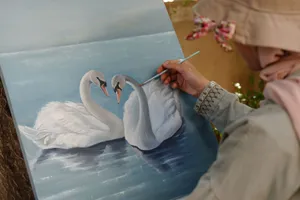 An artist paints two swans on a canvas in a Damascus art gallery. jigsaw puzzle