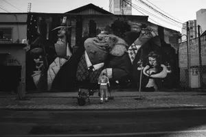 A city worker cleans the sidewalk in front of a large black and white mural depicting fictional characters. jigsaw puzzle