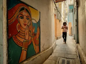 A child walks past vibrant street art in a narrow alleyway of Varanasi, India. jigsaw puzzle