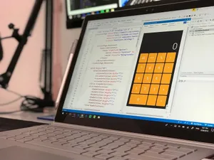 A laptop screen shows a coding application with a calculator design in a tech office setting. jigsaw puzzle