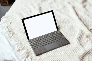 A sleek laptop with a blank screen sits on a soft, textured knit blanket, perfect for showcasing digital content. jigsaw puzzle