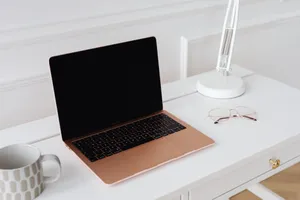 A modern sleek workspace featuring a laptop, desk lamp, and glasses on a white table. jigsaw puzzle