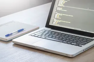 Laptop with code editor open, notebook and pen on wooden desk, perfect for tech and work themes. jigsaw puzzle