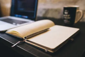 Open notebook with a pen on a wooden desk beside a laptop, ideal for blogging and work-related themes. jigsaw puzzle