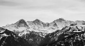 Black and white photo capturing majestic, snow-capped mountains in a serene winter landscape. jigsaw puzzle
