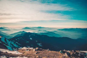 Captivating view of a mountain range stretching beneath a serene blue sky with clouds. jigsaw puzzle