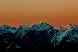 Stunning snow-covered mountains at sunset with an orange sky backdrop. jigsaw puzzle