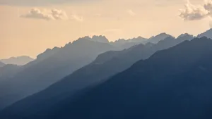 A tranquil view of layered mountains with fog at high altitude during the day. jigsaw puzzle