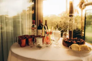 Sunlit party table with drinks, snacks, and flowers creating a warm, inviting atmosphere. jigsaw puzzle