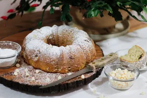 Delicious Bundt cake with powdered sugar and white chocolate on a wooden board, perfect for a sweet treat. jigsaw puzzle