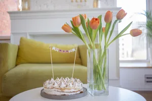 Beautiful cake with tulips in a glass vase on a table, perfect for celebrations in a cozy indoor setting. jigsaw puzzle