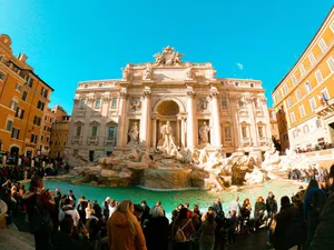 Crowd of people gathering near fountain with clean water on square outside historic palace in city jigsaw puzzle