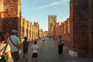 People walking on the historic Castelvecchio Bridge in Verona, Italy, with sunset lighting and ancient architecture. jigsaw puzzle