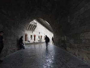 Silhouettes of people walking through a medieval stone tunnel on a rainy city day. jigsaw puzzle