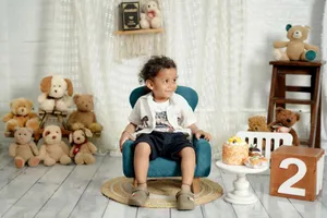 Young child celebrating birthday indoors surrounded by teddy bears and cake. jigsaw puzzle
