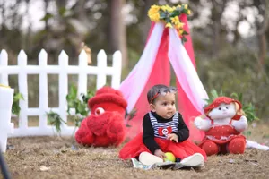 Adorable baby in a red dress sitting outdoors with colorful toys and decorations. jigsaw puzzle
