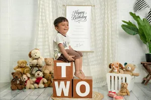 Cute toddler sitting on blocks with toys for a birthday celebration indoors. jigsaw puzzle