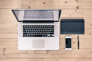 Top view of a tidy workspace featuring a laptop, smartphone, notebook, and pen on a wooden desk. jigsaw puzzle