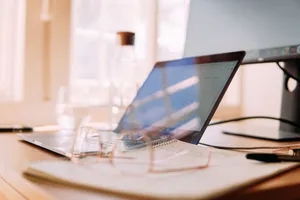 A well-lit home office setup featuring a laptop, monitor, and glasses, ideal for remote work. jigsaw puzzle