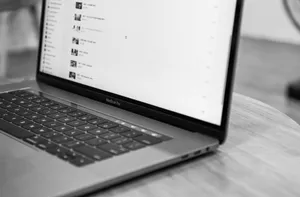 Black and white photo of a MacBook Pro on a round wooden table. jigsaw puzzle