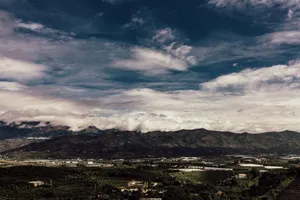 Breathtaking view of mountains under an expansive blue sky with clouds. jigsaw puzzle