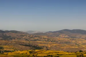 Vast view of rolling hills and distant mountains under clear blue skies. jigsaw puzzle