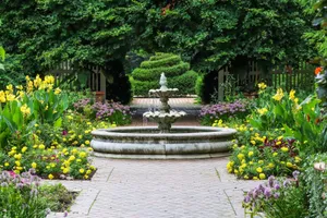 Beautiful, serene garden scene with vibrant flowers and a central stone fountain surrounded by lush greenery. jigsaw puzzle