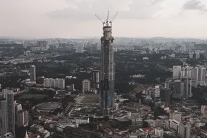 Aerial view of Kuala Lumpur showcasing a skyscraper under construction amid a sprawling urban landscape. jigsaw puzzle