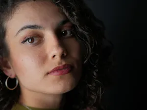 A striking close-up portrait of a woman with curly hair, large earrings, and a pensive expression. jigsaw puzzle