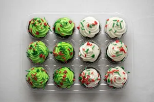 A tray of vibrant holiday-themed cupcakes with green and white frosting, decorated with colorful sprinkles. jigsaw puzzle