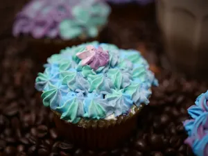 Close-up of a colorful cupcake with pastel frosting, surrounded by coffee beans. jigsaw puzzle