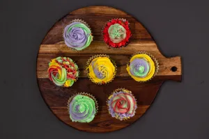 Vibrant cupcakes arranged on a wooden tray against a black background, perfect for dessert inspiration. jigsaw puzzle