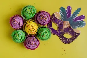 Vibrant Mardi Gras cupcakes with sprinkles and a decorative mask on yellow background. jigsaw puzzle