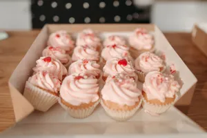 A close-up box of delectable pink frosted cupcakes ideal for dessert lovers. jigsaw puzzle