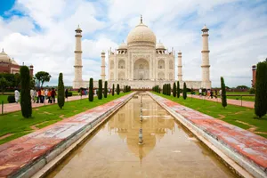 Iconic view of the Taj Mahal with lush gardens and reflecting pool under a cloudy sky in Agra, India. jigsaw puzzle