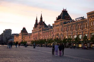 View of GUM Department Store lit up at twilight in Moscow's Red Square, with people strolling in the foreground. jigsaw puzzle