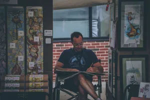Captured moment of a street artist sketching in an outdoor art booth with colorful designs. jigsaw puzzle