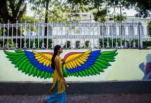 A woman walks by a vibrant wing mural painted on a wall outside a historical building. jigsaw puzzle