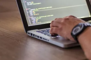 A close-up shot of a person coding on a laptop, focusing on the hands and screen. jigsaw puzzle