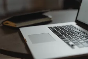 Close-up of a laptop keyboard on a desk with a notebook in soft focus. jigsaw puzzle
