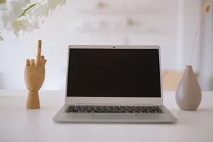 A minimalist workspace featuring a laptop with decorative items and floral arrangement. jigsaw puzzle