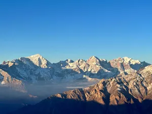 Majestic snow-covered mountain peaks under a clear blue sky captured at sunrise. jigsaw puzzle
