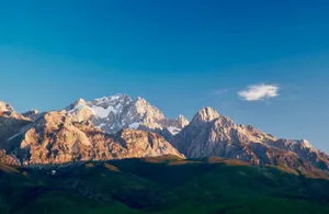 Capture the beauty of Jade Dragon Snow Mountain in Yunnan at sunrise with clear blue skies. jigsaw puzzle