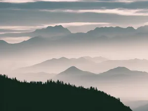 A tranquil view of mist-covered mountains and a forest under a cloudy sky. jigsaw puzzle